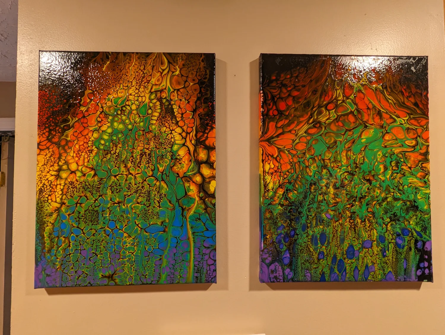 A matched pair of vivid green, orange and black paintings displayed together.