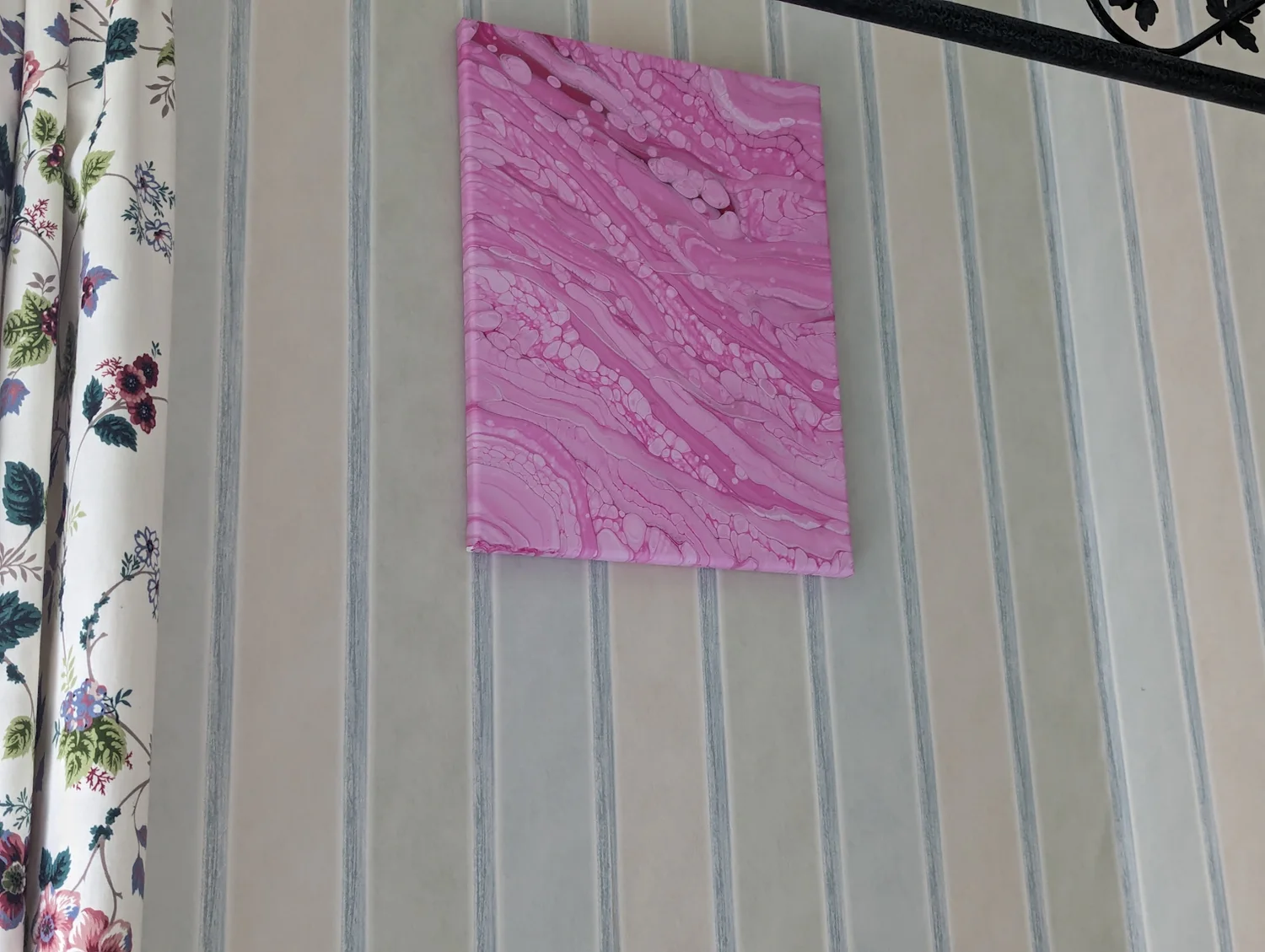 A pink fluid-art painting displayed on a paneled wall.