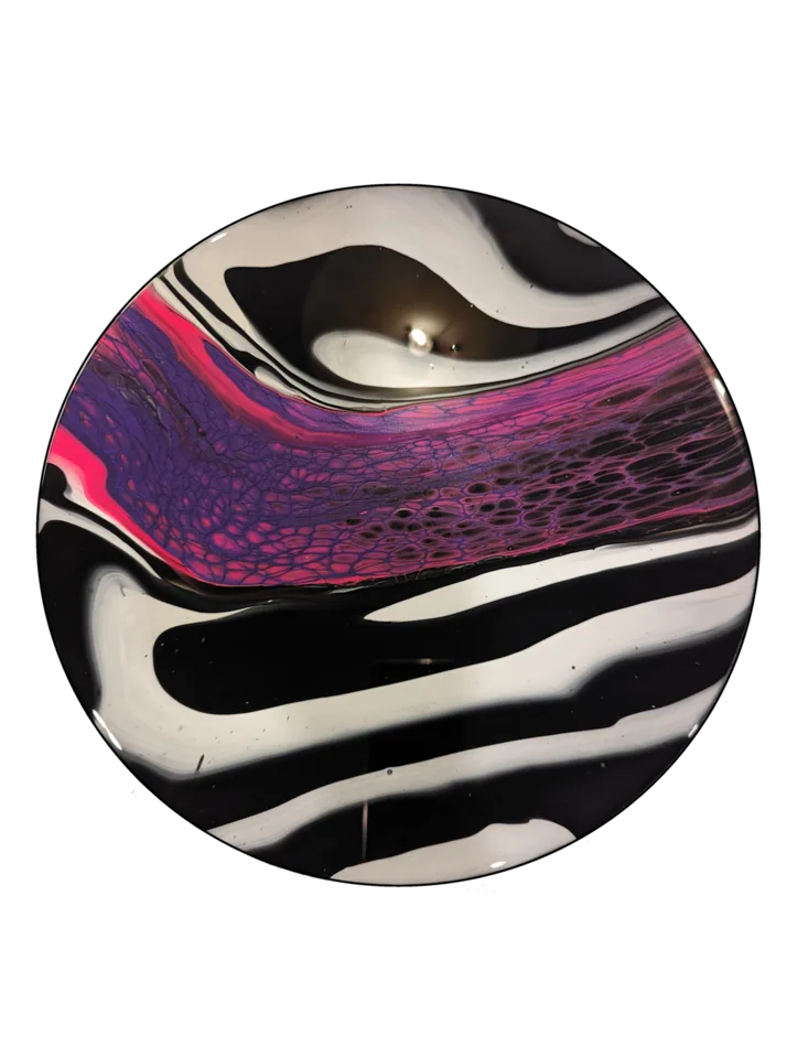 Round black and white striped piece crossed by a vivid magenta cellular band.